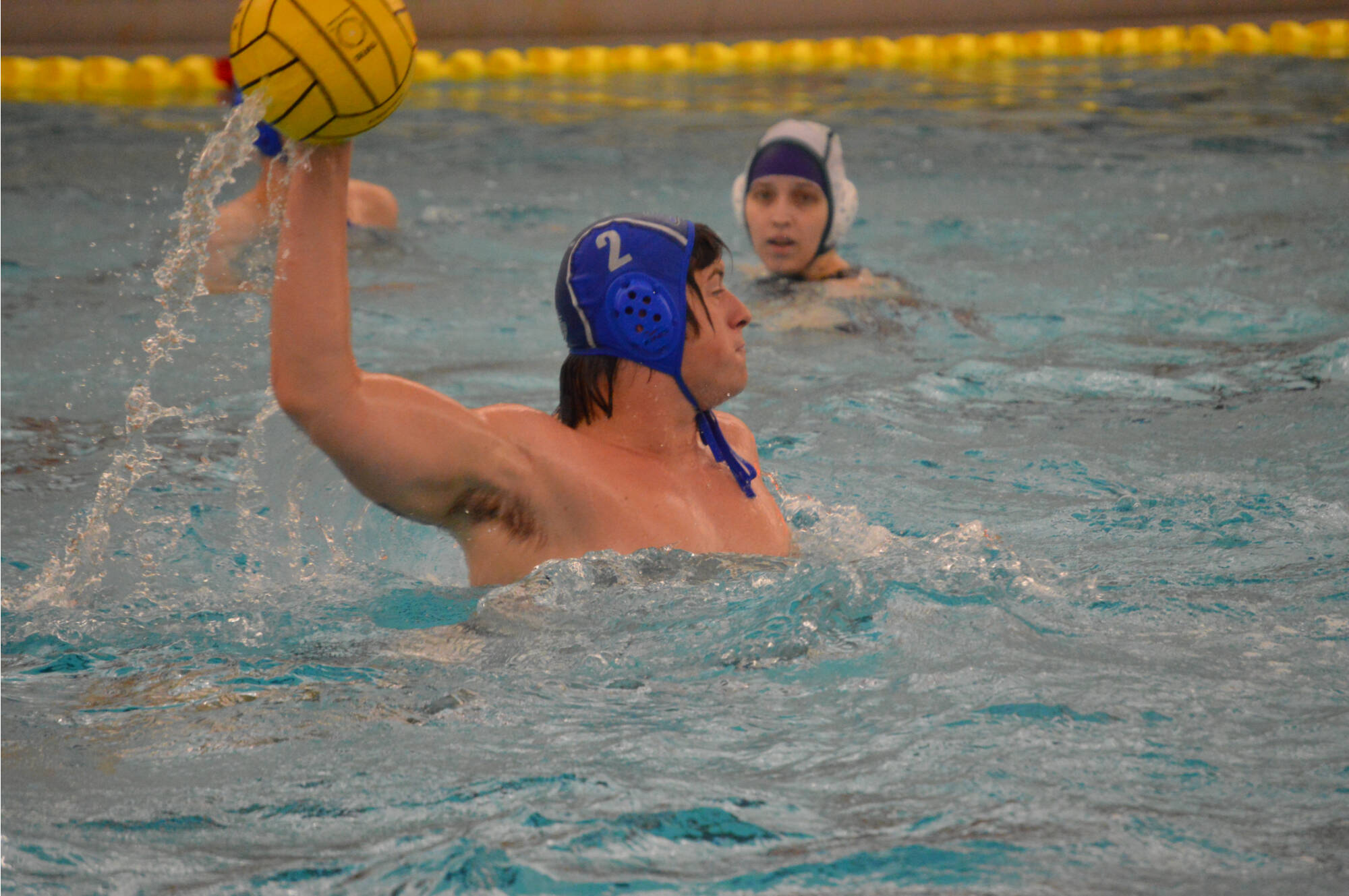 Water polo player (2) holding ball over head ready to shoot.